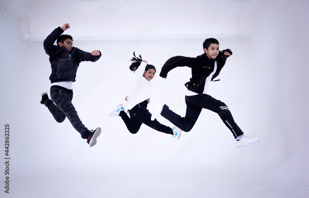 three kid jumping and trainer dancing isolated on white background. Portrait of kid dancer jumping in studio.