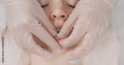Young woman on a buccal massage in the spa salon. Massage the face close-up. Hands of a masseur in gloves doing massage photo
