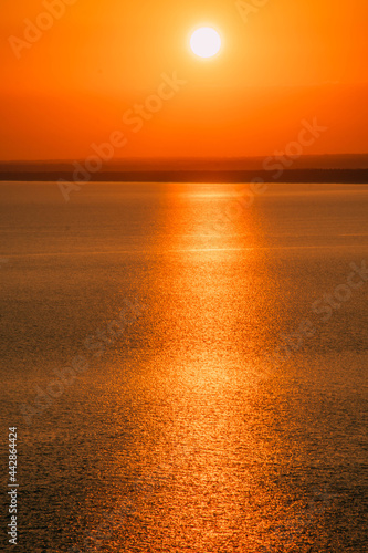 a bright sunset on the coast with a bright reflection path on the water