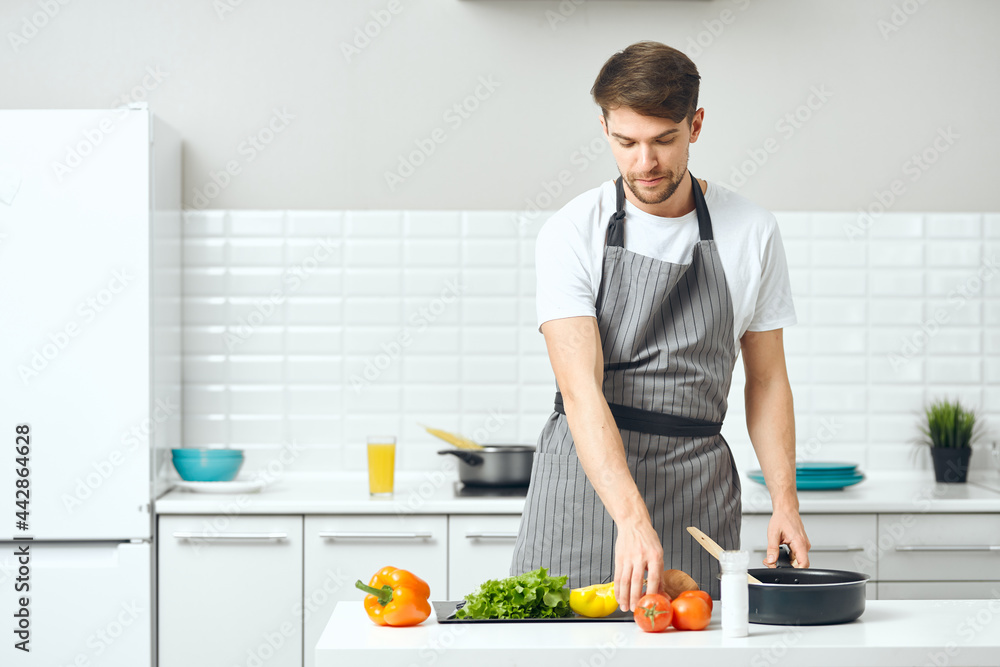 man in an apron at home in the kitchen cooking man in an apron at home in the kitchen cooking