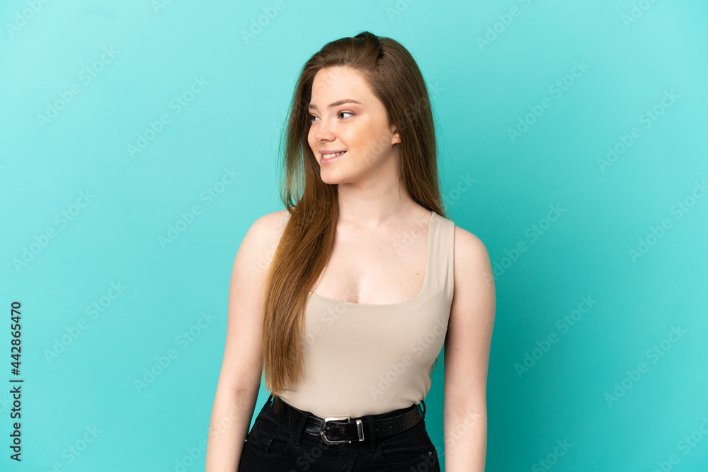 Teenager girl over isolated blue background looking side Teenager girl over isolated blue background looking side