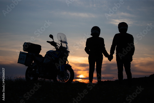 Silhouette of lover couple in sunset with motorcycle in sunset.