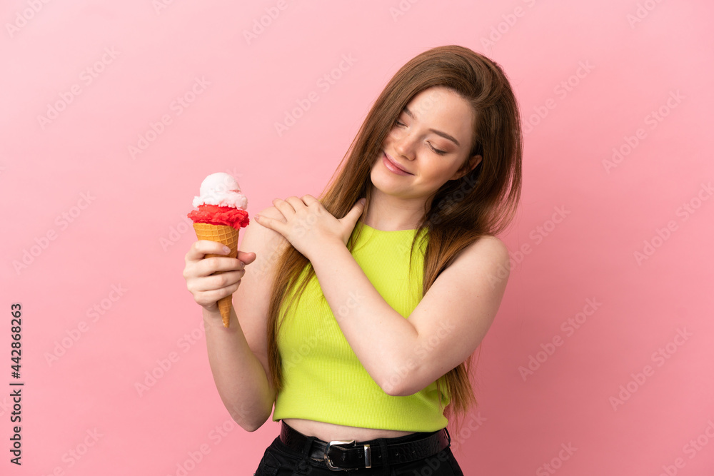 Teenager girl with a cornet ice cream over isolated pink background suffering from pain in shoulder for having made an effort Teenager girl with a cornet ice cream over isolated pink background suffering from pain in shoulder for having made an effort