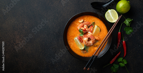 Tom Yum kung Spicy Thai soup with shrimp in a black bowl on a dark background, top view photo