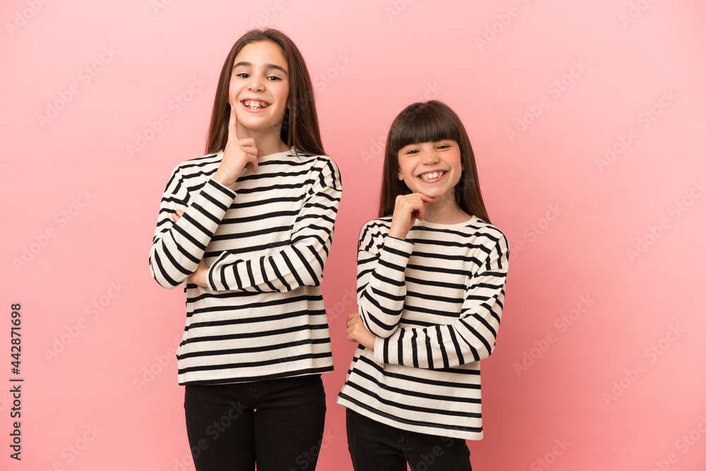 Little sisters girls isolated on pink background smiling with a sweet expression Little sisters girls isolated on pink background smiling with a sweet expression