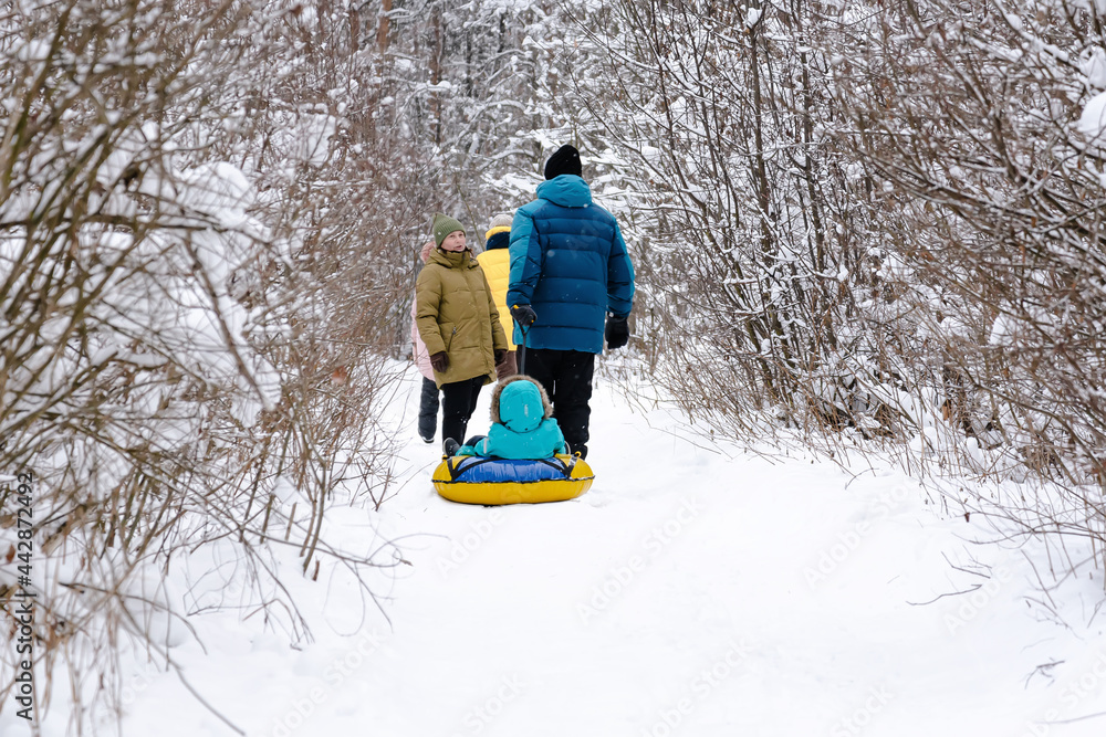 A married couple with children and friends go for a walk in the winter snow-covered forest. People, lifestyle concept