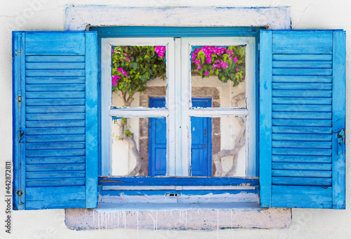 Iconic blue wooden window on white stone wall of typical Greek house, Greece