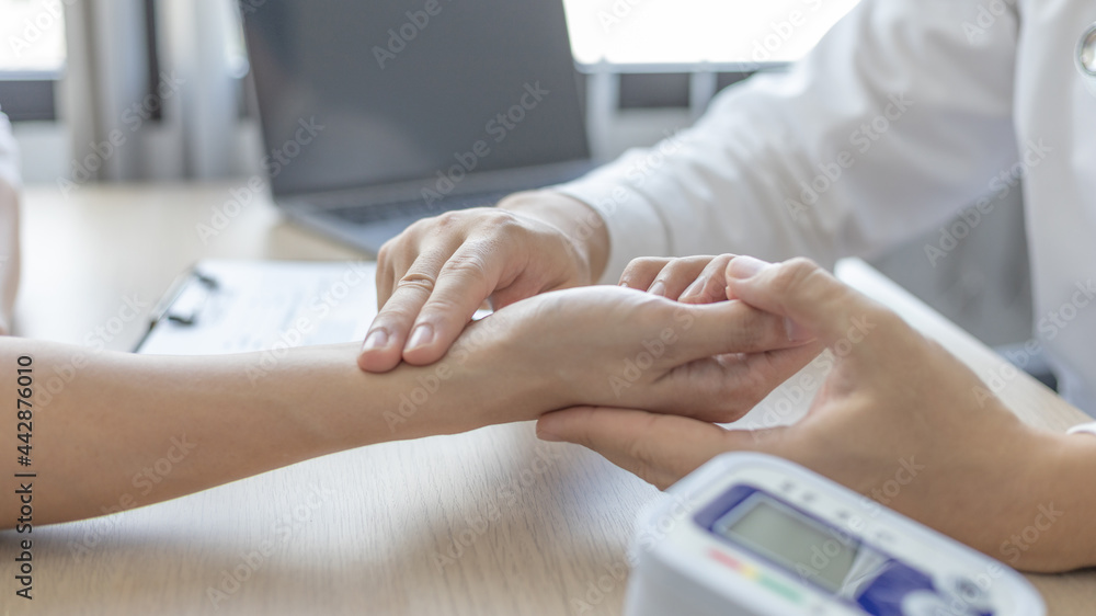 Medical professional measures the pulse of a male patient's wrist to check his heart rate in the hospital's examination room, Doctor checking patient health, Initial symptom check.