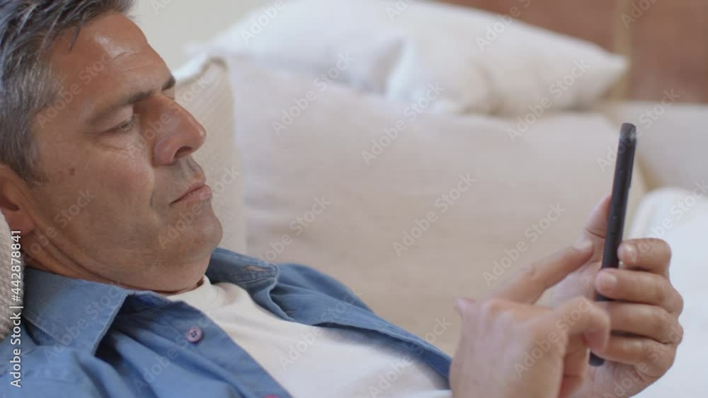 Close Up Shot of a Middle Aged Man Slouched On Sofa Using Smartphone Close Up Shot of a Middle Aged Man Slouched On Sofa Using Smartphone
