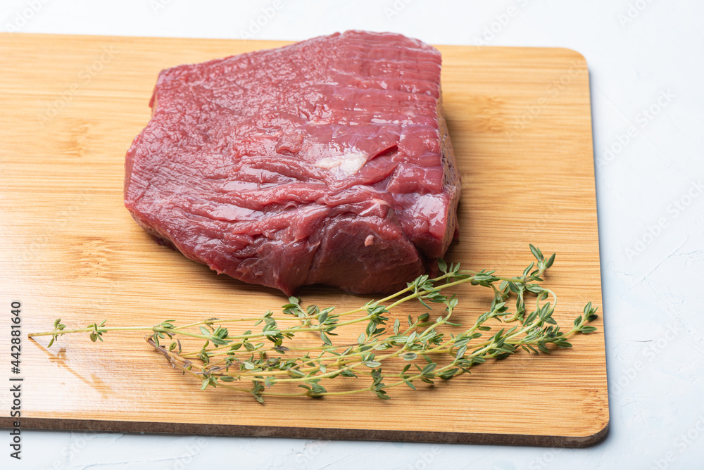 Raw beef on a wooden cutting board with thyme. Raw beef on a wooden cutting board with thyme.