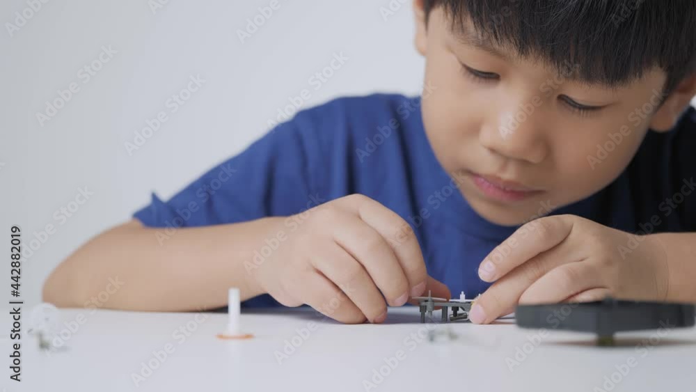 Asian boy playing with mechanical gear kit. A 5 years old kid learns and studies basic engineering through the clock part. Asian boy playing with mechanical gear kit. A 5 years old kid learns and studies basic engineering through the clock part.