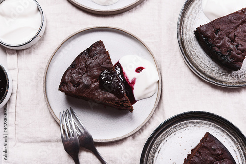 Slices of rich moist chocolate cherry cake. Homemade dark chocolate sweet brownies cakes with ice cream on greige linen tablecloth. Selective focus
