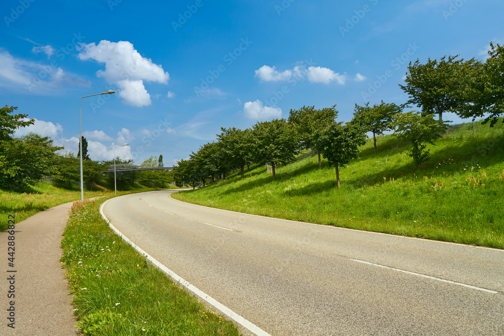 Leere Straße mit Kurve und Bürgersteig im Sommer