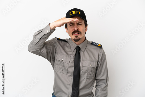 Young caucasian security man isolated on white background looking far away with hand to look something