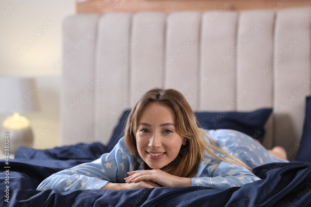 Young woman lying on comfortable bed with silky linens Young woman lying on comfortable bed with silky linens
