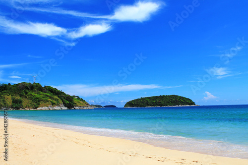 beautiful sandy beach with blue ocean and green island in the background, summer concept