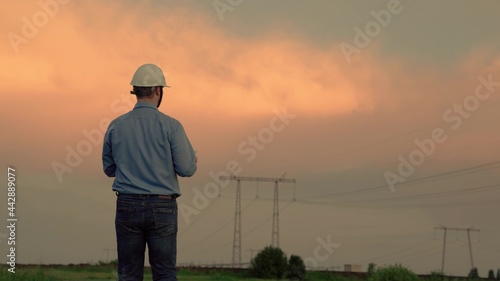 Modern electrical engineer, working on digital tablet. An electrical engineer works with computer tablet, works with electricity next to an electric tower. Industry of energy business technologies.