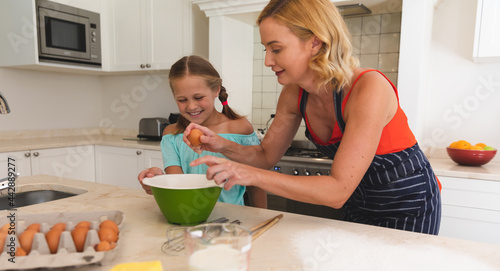 Caucasian mother and daughter baking and smiling in kitchen