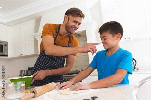 Caucasian father and son baking and smiling in kitchen