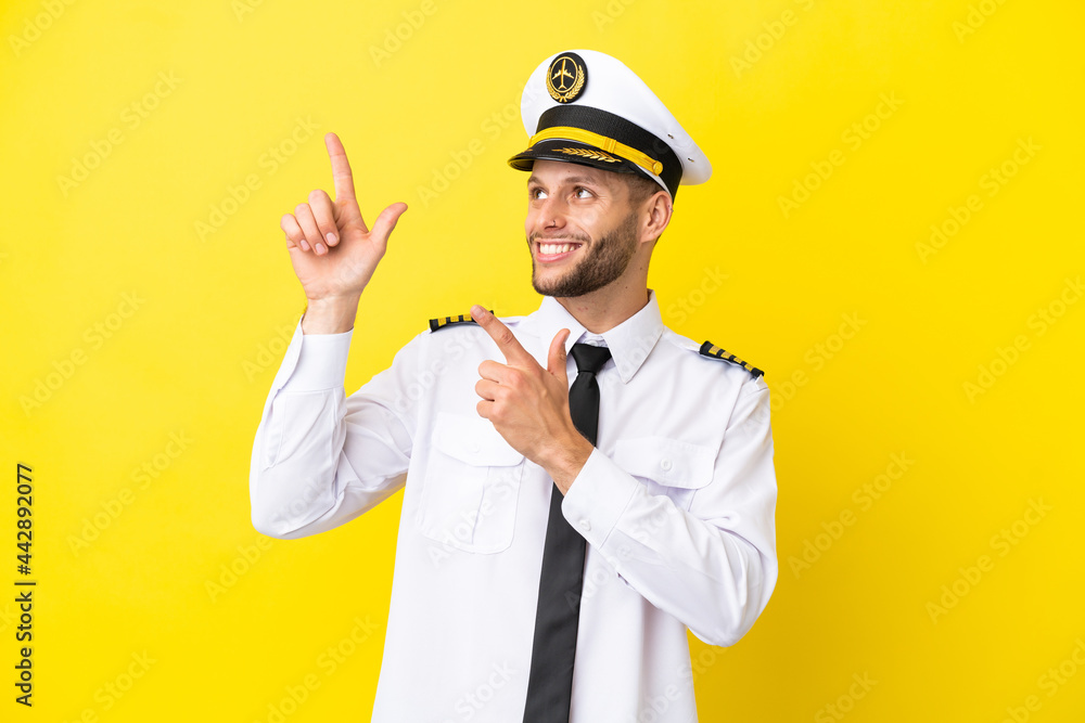 Airplane caucasian pilot isolated on yellow background pointing with the index finger a great idea Airplane caucasian pilot isolated on yellow background pointing with the index finger a great idea