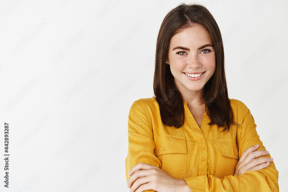 Close-up of professional young business woman smiling at camera, cross arms on chest and looking confident, standing over white background Close-up of professional young business woman smiling at camera, cross arms on chest and looking confident, standing over white background