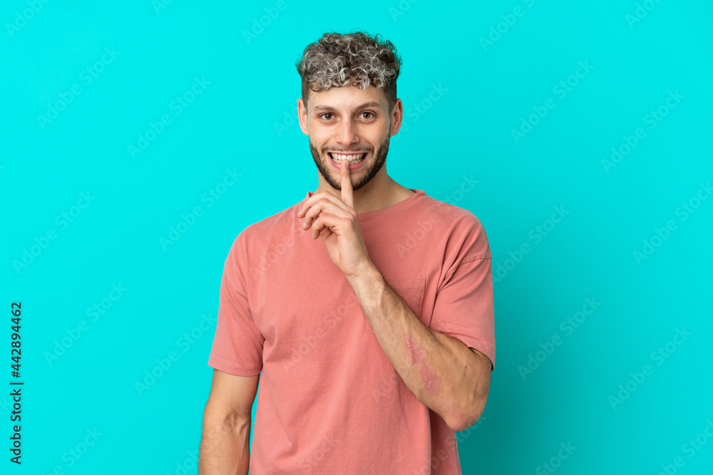 Young handsome caucasian man isolated on blue background showing a sign of silence gesture putting finger in mouth Young handsome caucasian man isolated on blue background showing a sign of silence gesture putting finger in mouth