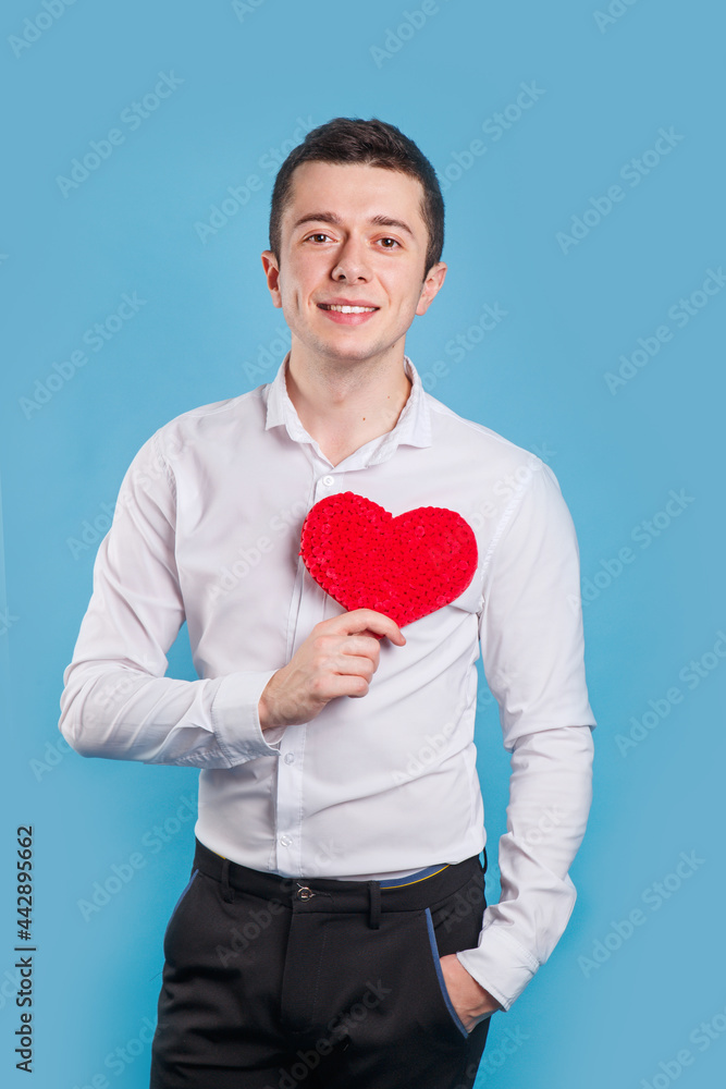Cute handsome man holdiing red heart made of paper for Valentines Day on blue background
