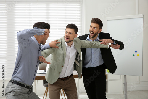 Canvas Print Man interrupting colleagues fight at work in office