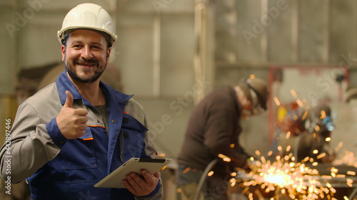 Photos Engineer looking at camera smiling and showing thumb up at metallurgy plant