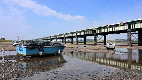 Boats beached on the River Adur at Shoreham during low tide with beautiful reflections of the boats as a train crosses the Railway Bridge crossing the river.