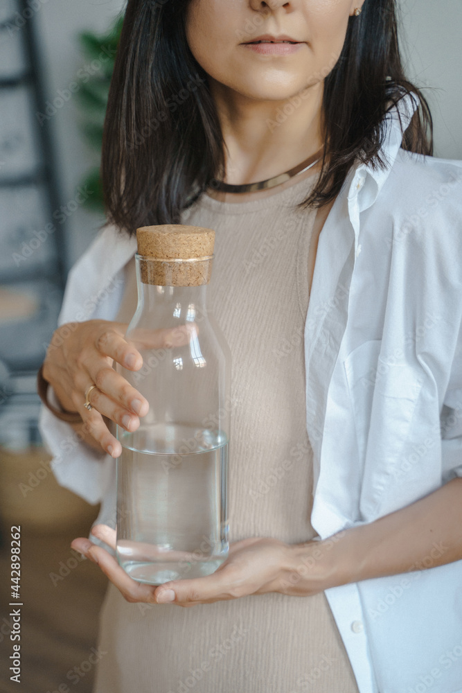 Unrecognizable young woman holding a jug of clean water in her hands. Naturalness, purity and healthy lifestyle concept Unrecognizable young woman holding a jug of clean water in her hands. Naturalness, purity and healthy lifestyle concept