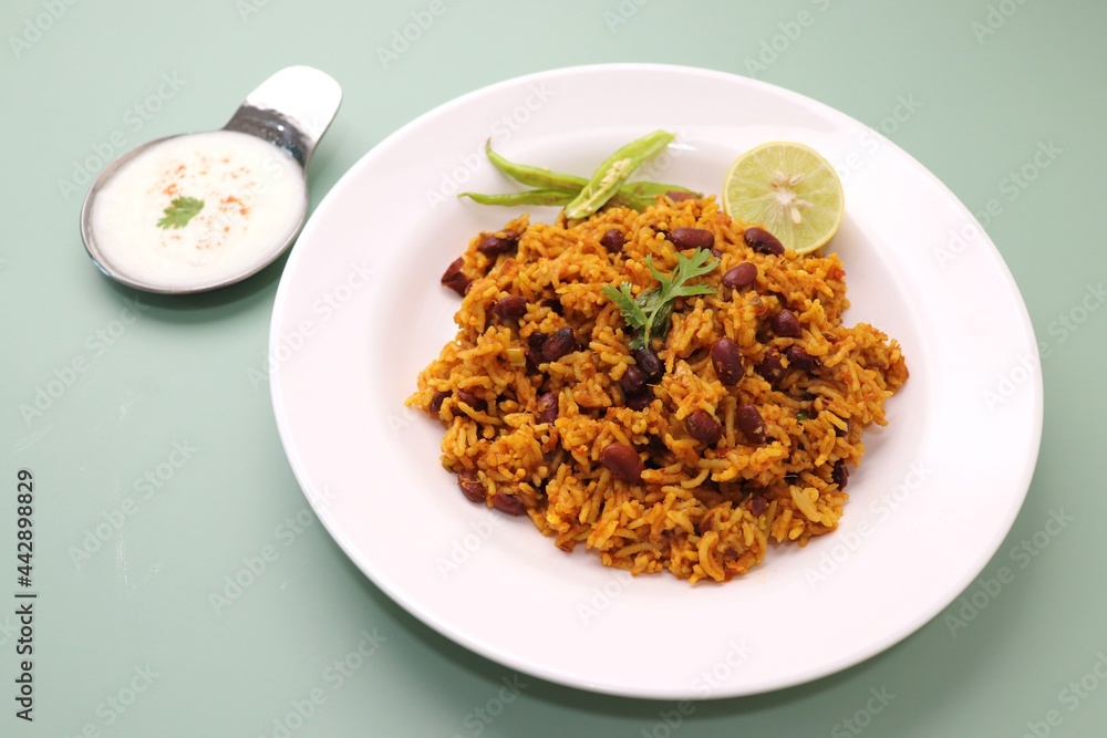 Indian cuisine - Kidney Beans Biryani, Rajma Pulao. Garnished with chopped coriander, and lemon wedges. Rajma biryani served with dahi. Along with copy space. Rajma Chawal flatlay.