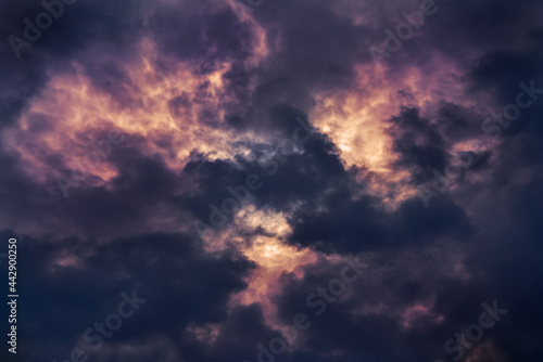 Dramatic dark clouds on the sky with red and orange areas where the sun shines through © JGade