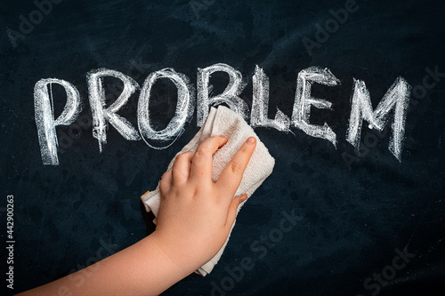 Hand wiping off chalk word PROBLEM on black chalkboard using rag. Remove problem issue solution concept