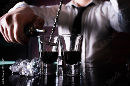 Barman preparing cocktail shots at the bar counter. Barman mixing drinks at the night club.