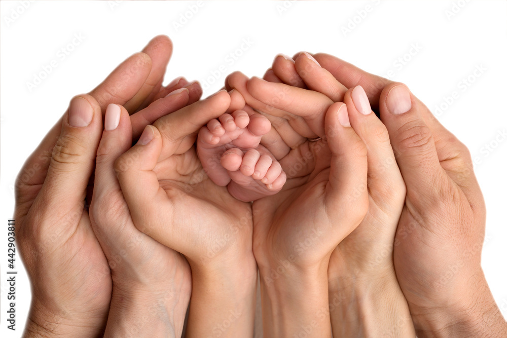 The hands of the mother, father and older child hold the feet of the newborn. Cute family portrait with baby. On a black studio background.