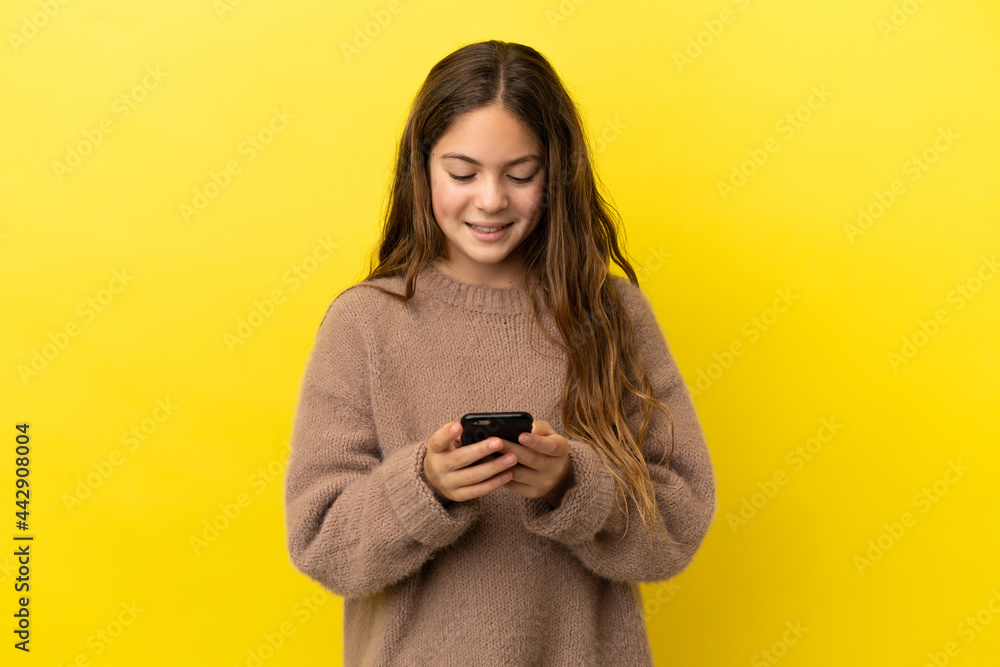 Little caucasian girl isolated on yellow background sending a message with the mobile Little caucasian girl isolated on yellow background sending a message with the mobile