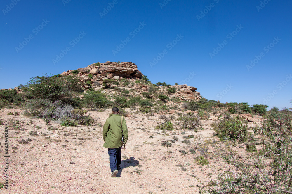 Back view of a Somalilander soldier walking towards a rocky hill