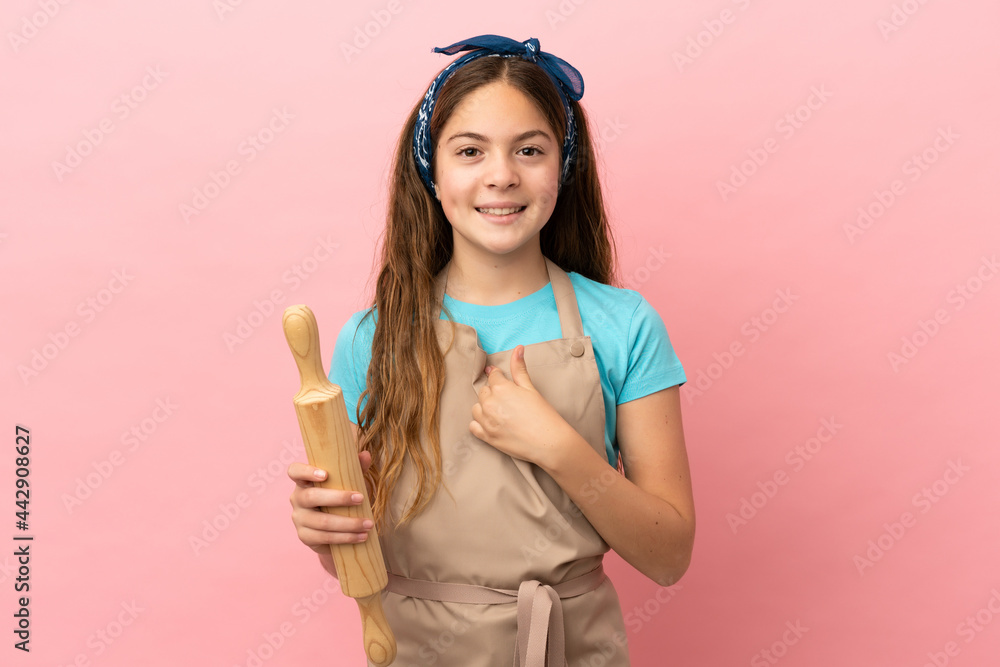 Little caucasian girl holding a rolling pin isolated on pink background with surprise facial expression Little caucasian girl holding a rolling pin isolated on pink background with surprise facial expression
