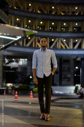 Full length portrait of handsome black African businessman outdoors in city at night © Ranta Images