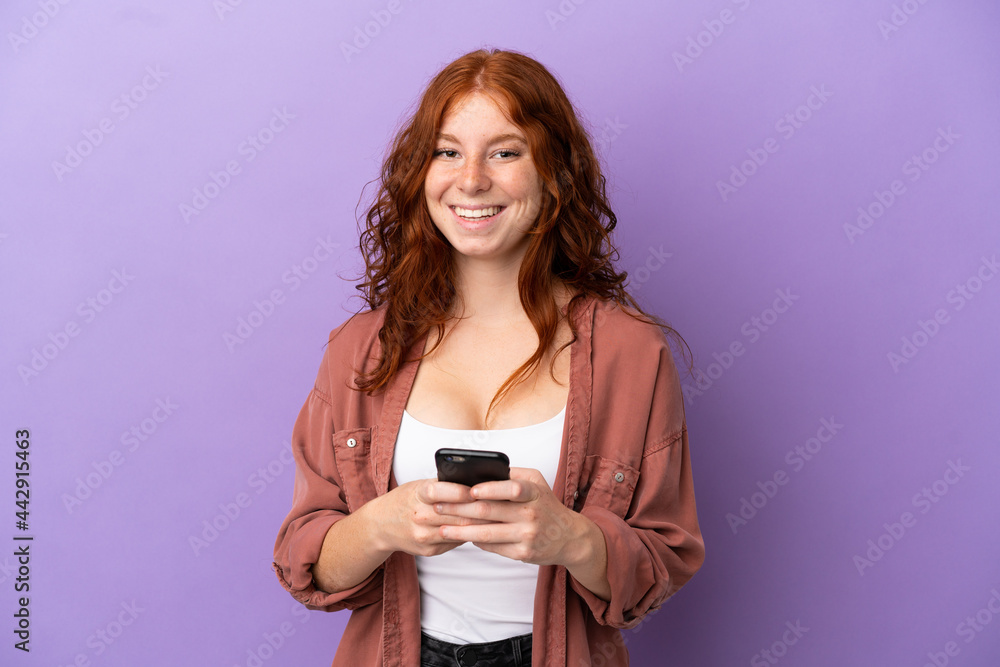Teenager redhead girl over isolated purple background surprised and sending a message Teenager redhead girl over isolated purple background surprised and sending a message