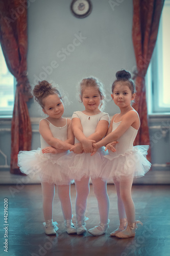 Three funny little ballerinas in tutus are in the ballet class. Image with selective focus and toning