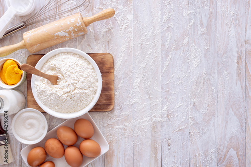 Homemade dough recipe (eggs, flour, milk, sugar) on a wooden table top view.