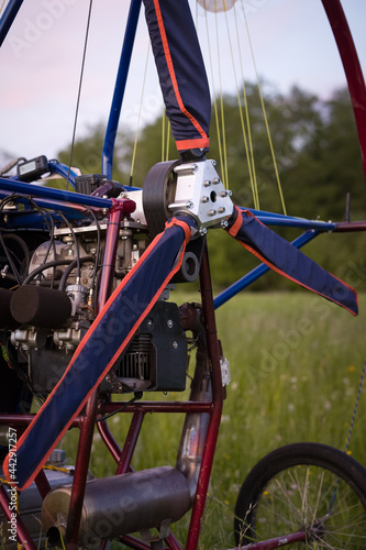 A closeup of a motorized paraglider trolley with a non-revolving engine and a sheathed propeller on an airfield in the late evening. Extreme sports. Paragliding and small aircraft.