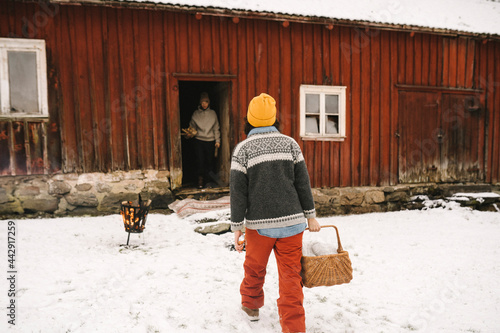 Kvinna med korg går mot stuga under vintern photo