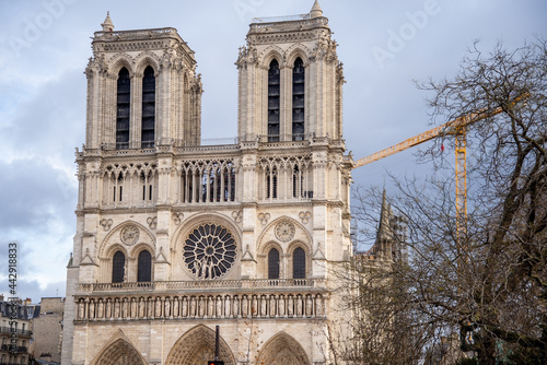 Famous facade of Notre-Dame de Paris with tower crane on background