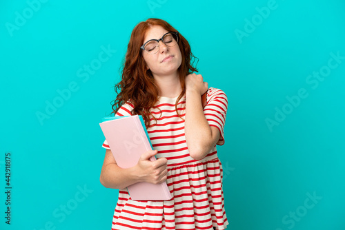 Student teenager redhead girl isolated on blue background suffering from pain in shoulder for having made an effort