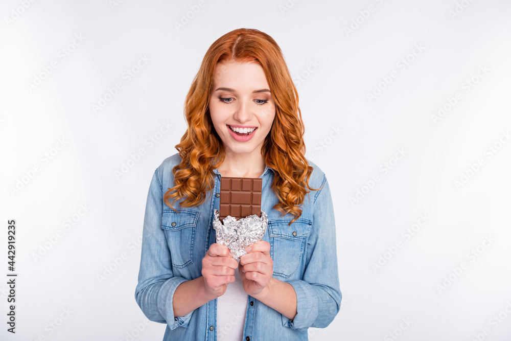 Photo of attractive young positive lady look bar of chocolate hungry sweets isolated on grey color background Photo of attractive young positive lady look bar of chocolate hungry sweets isolated on grey color background