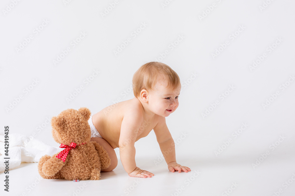 baby boy in a diaper sits on a white background with a teddy bear baby boy in a diaper sits on a white background with a teddy bear