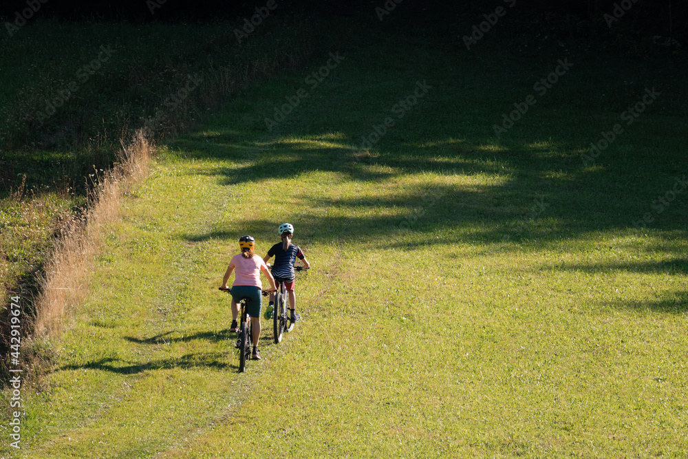 Fototapeta premium Two girls on mtb bikes. Mother and daughter riding on a trail.